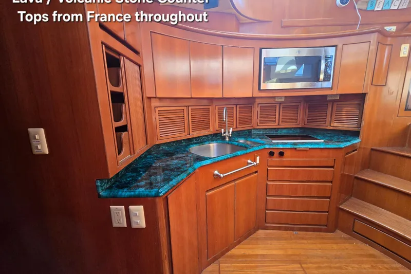 Slide: The Image of Luxurious yacht kitchen with volcanic stone countertop, wooden cabinetry, and modern appliances. - 32