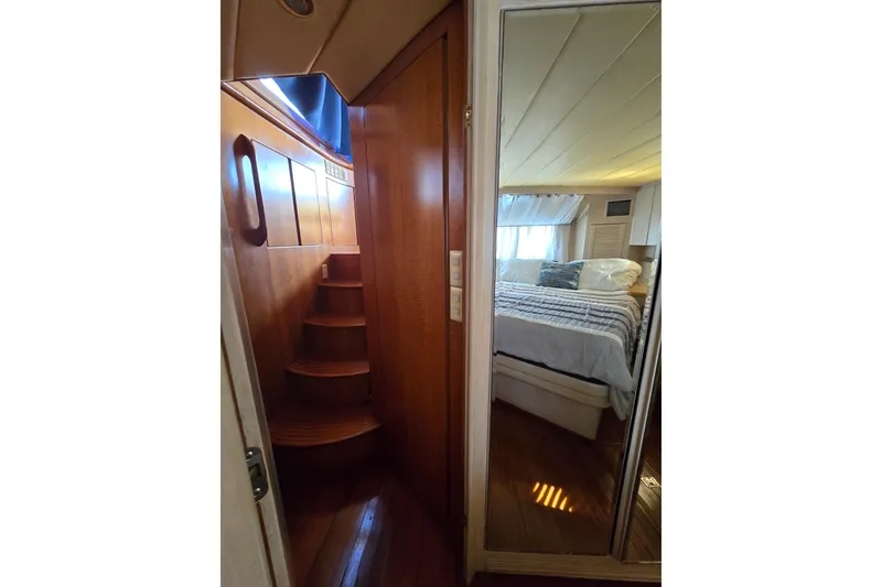 Slide: The Image of Interior of a 1996 President 58 yacht, featuring wooden stairs and a cozy bedroom. - 42