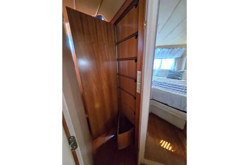 Slide: The Image of Wooden interior of a 1996 President 58 yacht, featuring a cozy bedroom and storage area. - 43