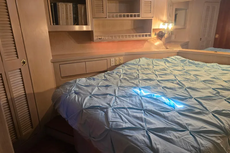 Slide: The Image of Cozy bedroom in a 1996 President 58 yacht with blue bedding and wooden cabinetry. - 48