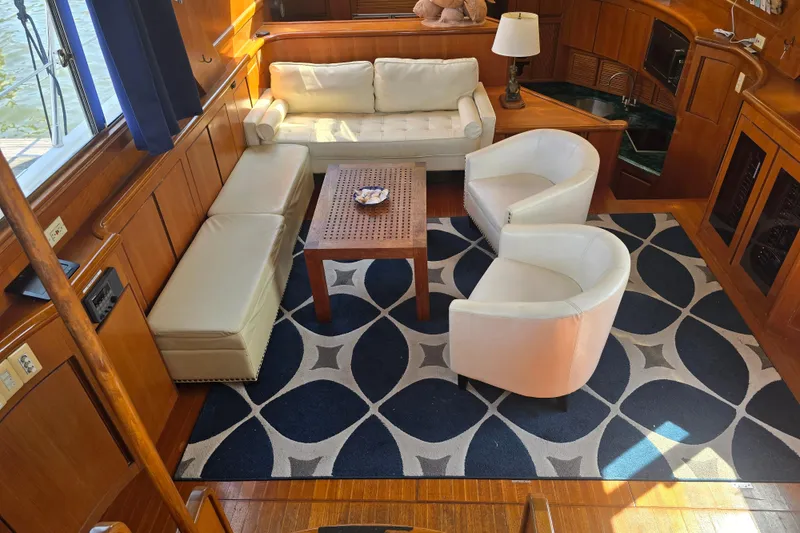 Slide: The Image of Luxurious yacht interior with white seating, wooden accents, and geometric rug, President 58, 1996 model. - 52