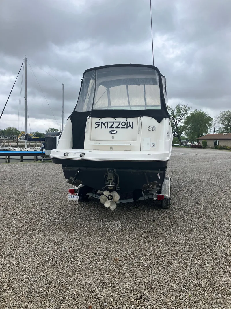 Slide: The Image of 2008 Rinker 260 Express Cruiser on gravel lot, cloudy sky. - 2