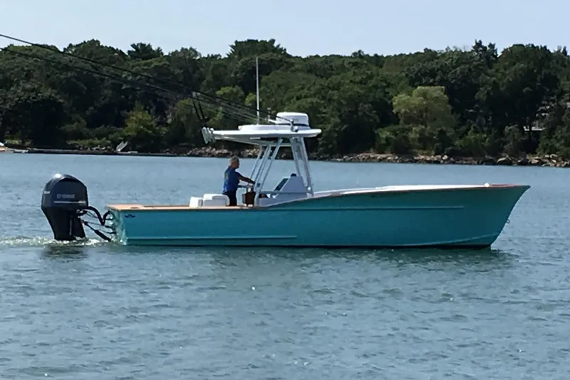 The Image of 2017 Harrison Boatworks 28 Center Console cruising on a calm lake with lush green shoreline. - 0