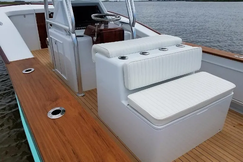Slide: The Image of 2017 Harrison Boatworks 28 Center Console with white seating and wooden deck on water. - 10