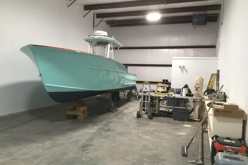 Slide: The Image of 2017 Harrison Boatworks 28 Center Console in a garage with tools and equipment. - 5