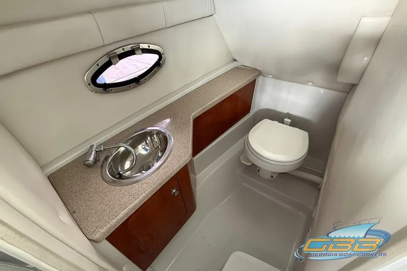 Slide: The Image of 2009 Crownline 300 LS boat bathroom with sink, toilet, and porthole window. - 27