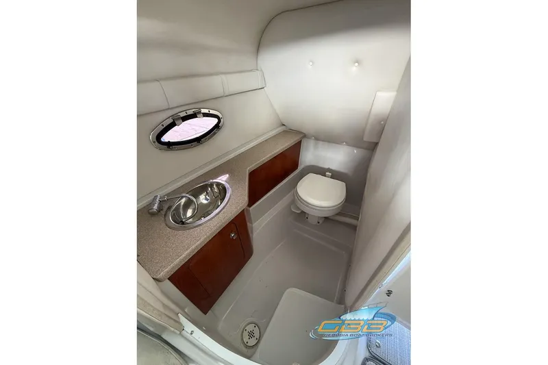 Slide: The Image of 2009 Crownline 300 LS boat bathroom with sink, toilet, and porthole window. - 28