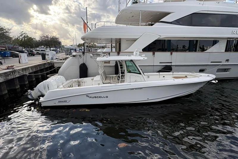 The Image of 2017 Boston Whaler 350 Outrage boat docked beside a larger yacht. - 1