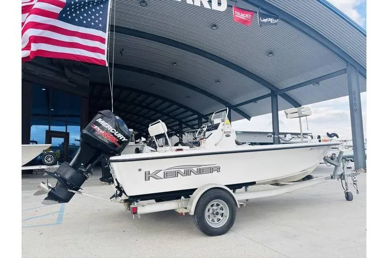 Slide: The Image of 2008 Kenner Vision 1800 boat on trailer, displayed outdoors under a canopy with American flag. - 2