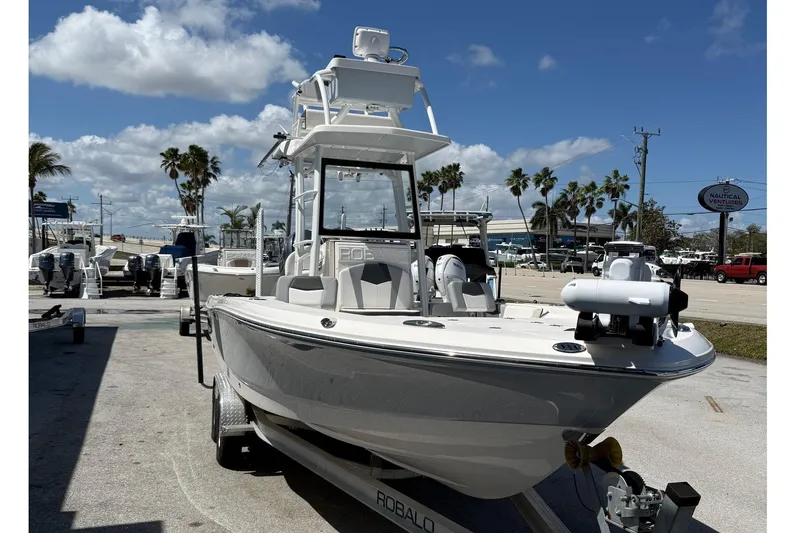 Slide: The Image of 2023 Robalo 246 Cayman SD boat on trailer under clear blue sky. - 2
