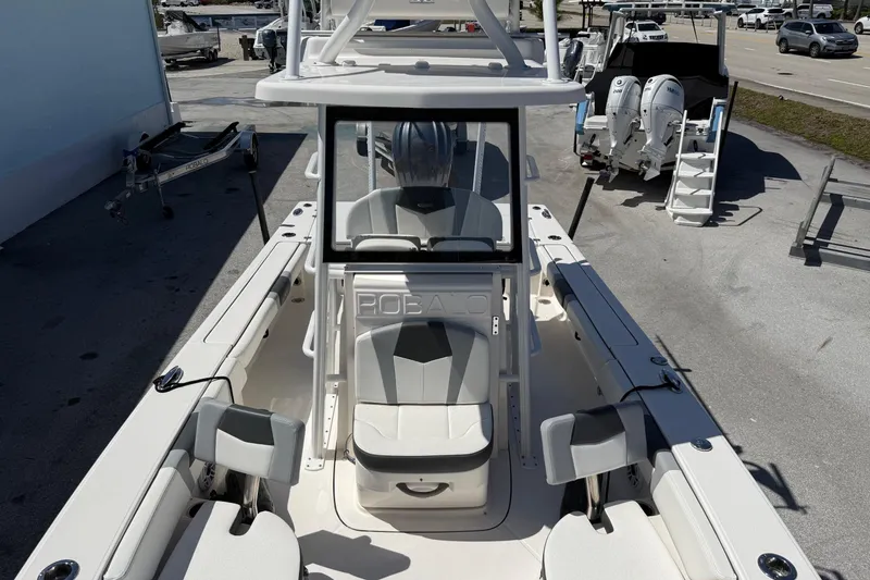 Slide: The Image of 2023 Robalo 246 Cayman SD boat interior with seating and console, parked outdoors. - 5