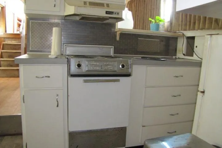 Slide: The Image of 1973 Chris-Craft 55 Commander kitchen with vintage stove, white cabinets, and a small plant. - 31