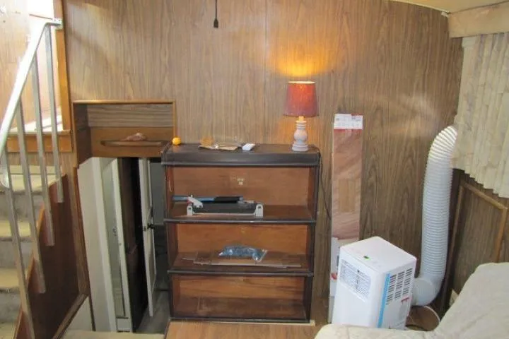 Slide: The Image of 1973 Chris-Craft 55 Commander interior with wood paneling, stairs, and a lamp-lit dresser. - 37