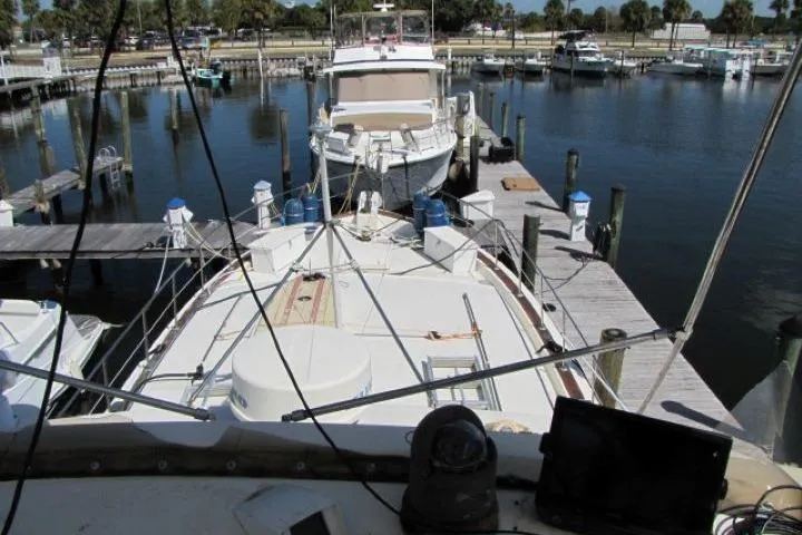 Slide: The Image of 1973 Chris-Craft 55 Commander yacht docked at a marina, surrounded by calm waters. - 4