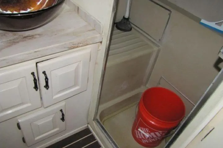 Slide: The Image of 1973 Chris-Craft 55 Commander interior with cabinets and a red bucket in the shower area. - 54