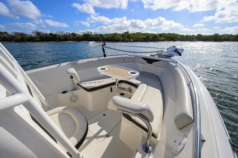 Slide: The Image of 2022 Sailfish 242 CC boat interior with seating and table on a sunny day. - 17