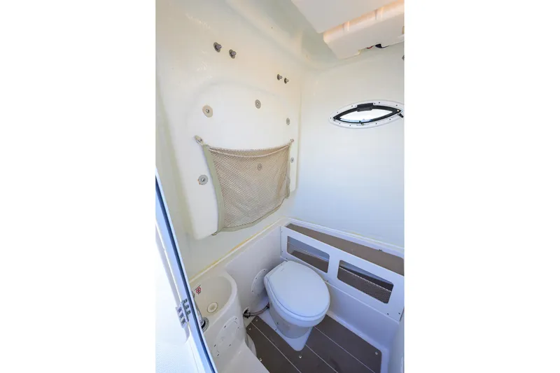 Slide: The Image of 2022 Sailfish 242 CC boat interior with compact marine toilet and storage net. - 21