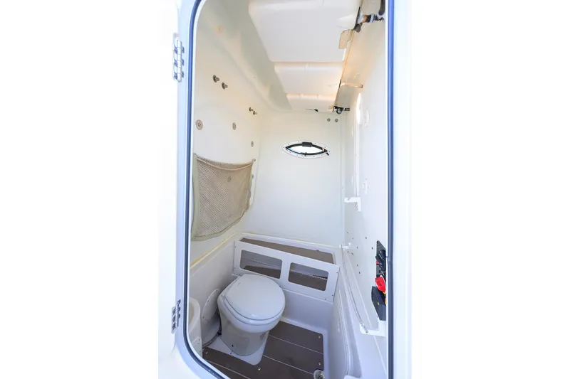 Slide: The Image of 2022 Sailfish 242 CC boat interior with compact marine toilet and storage. - 22