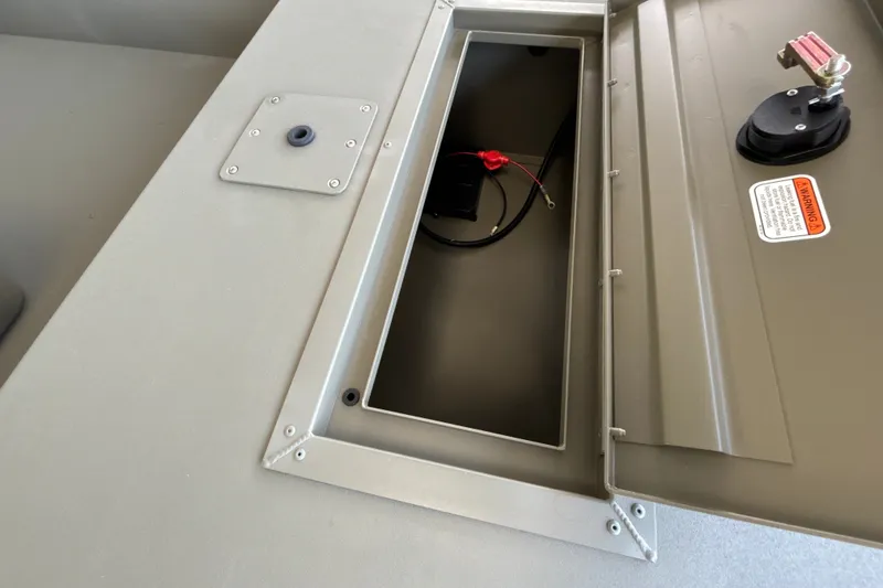 Slide: The Image of Open storage compartment in 2026 Tracker Grizzly 1648 SC boat, showing wiring and warning label. - 14