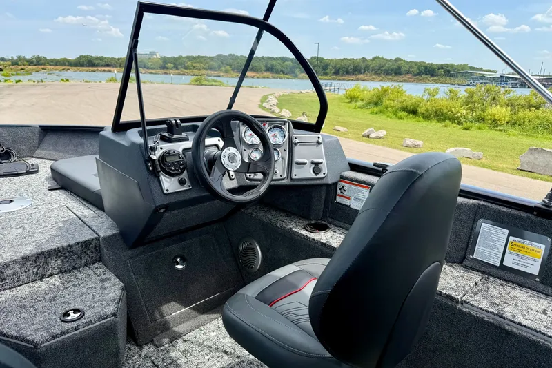 Slide: The Image of 2026 Tracker Pro Guide V-175 Combo boat interior with steering wheel and dashboard, near a scenic lake. - 7