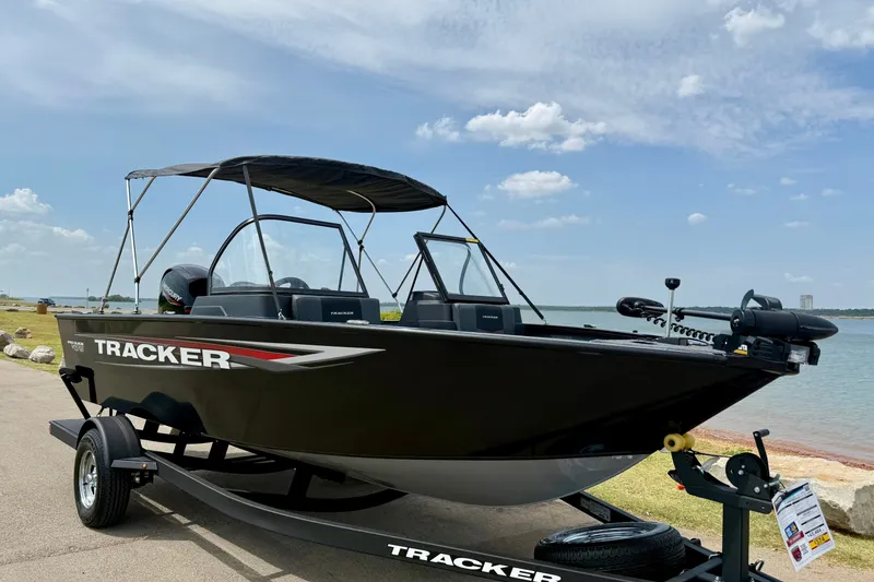 Slide: The Image of 2026 Tracker Pro Guide V-175 Combo boat on trailer by a lake under blue sky. - 2