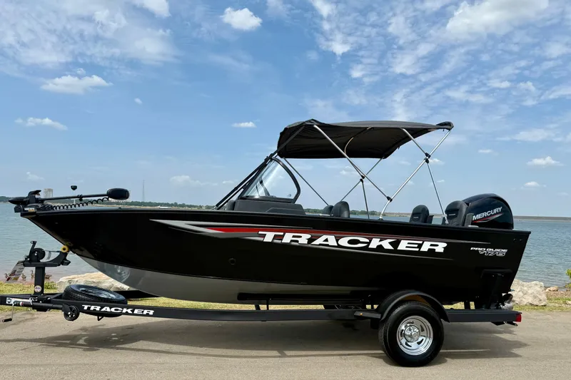 Slide: The Image of 2026 Tracker Pro Guide V-175 Combo boat by a lake under a blue sky. - 16