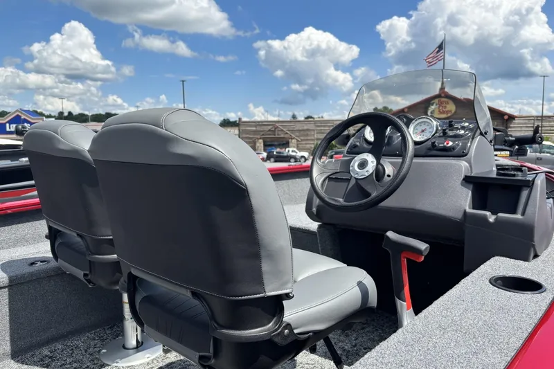 Slide: The Image of 2026 Tracker Super Guide V-16 SC boat interior with steering wheel and seats under blue sky. - 2