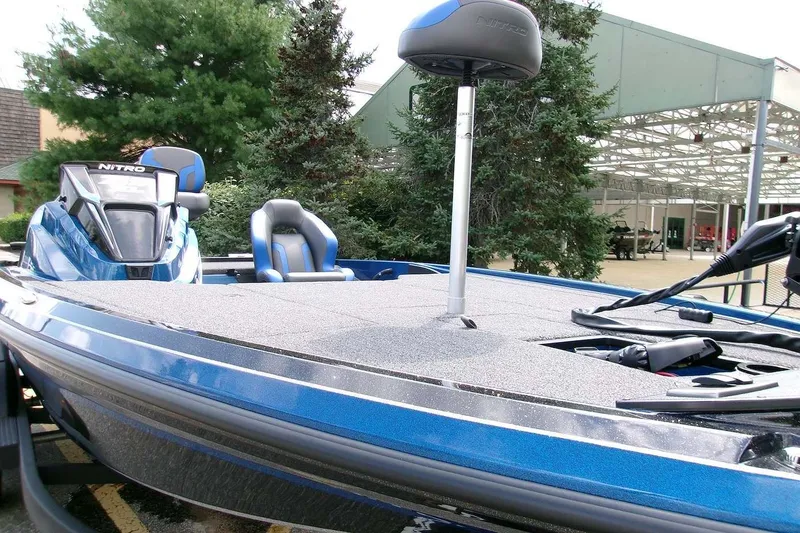 Slide: The Image of 2026 Nitro Z19 XL boat with blue exterior, parked outdoors near trees. - 2
