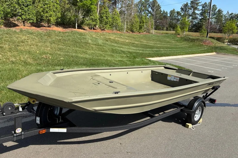 Slide: The Image of 2026 Tracker Grizzly 1754 Utility boat on trailer, parked in a lot with green grass background. - 2