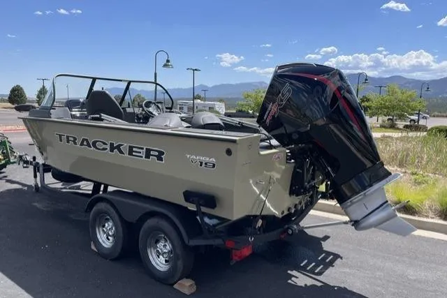 Slide: The Image of 2026 Tracker Targa V-19 WT boat on trailer, parked outdoors under clear blue sky. - 2