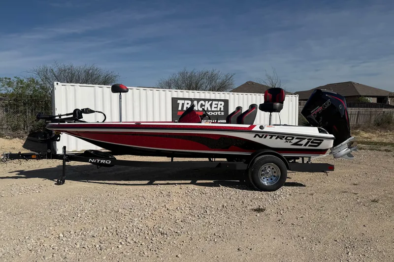 The Image of 2026 Nitro Z19 XL boat on trailer, parked outdoors near a storage container. - 0