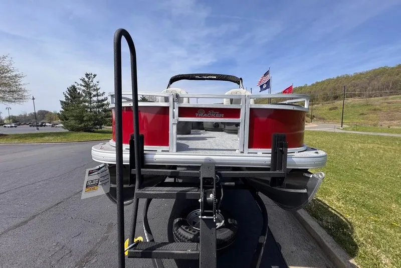 Slide: The Image of 2026 Sun Tracker Bass Buggy 18 DLX pontoon boat on trailer, parked outdoors. - 4