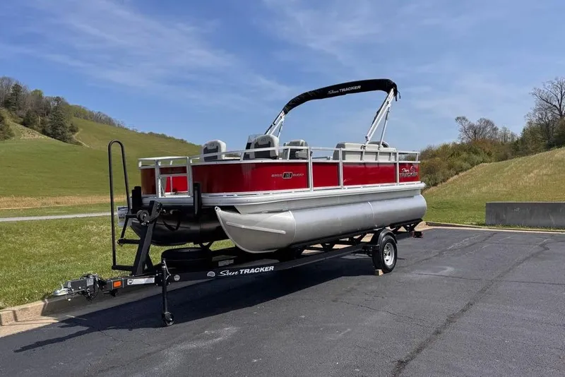 Slide: The Image of 2026 Sun Tracker Bass Buggy 18 DLX pontoon boat on trailer, parked outdoors. - 5