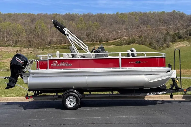 Slide: The Image of 2026 Sun Tracker Bass Buggy 18 DLX pontoon boat on trailer, scenic background. - 7