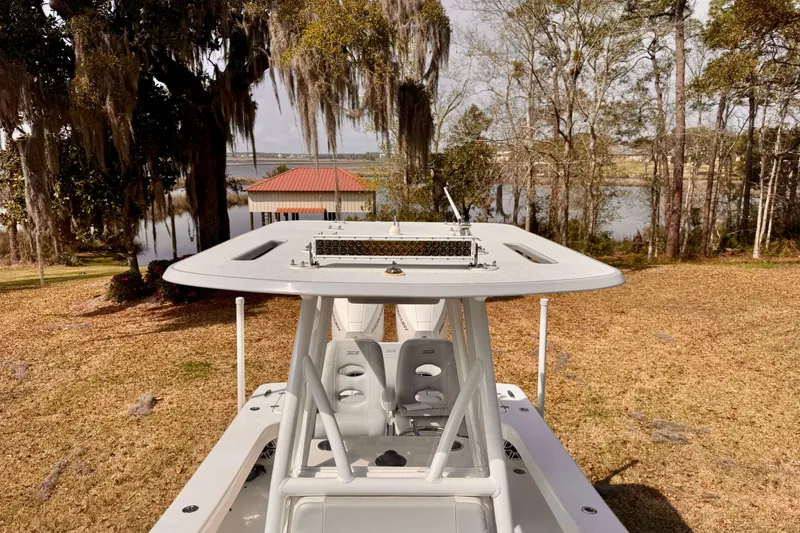 Slide: The Image of 2021 ZCB 26 Freemason boat with T-top, parked near a scenic lakeside view. - 10