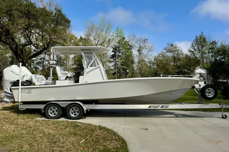 Slide: The Image of 2021 ZCB 26 Freemason boat on trailer, parked outdoors with trees in background. - 2