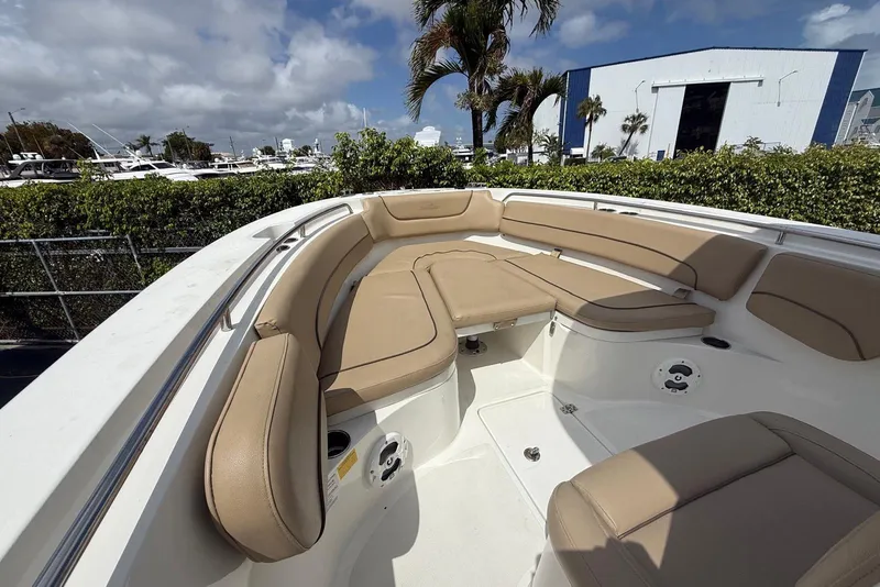 Slide: The Image of 2019 NauticStar 2602 Legacy boat with tan seating, docked near palm trees and a blue building. - 10
