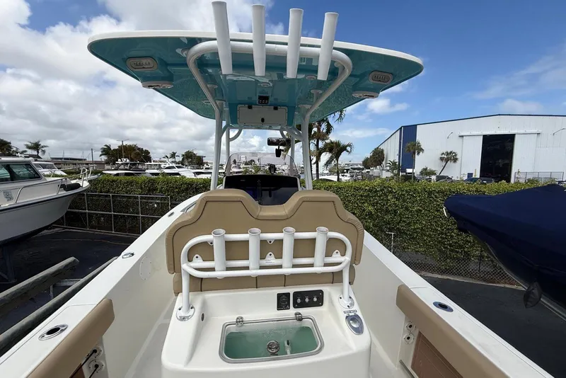 Slide: The Image of 2019 NauticStar 2602 Legacy boat with rod holders and seating, docked under a blue sky. - 11