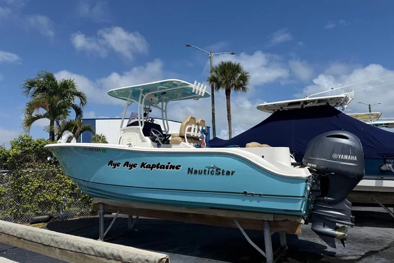Slide: The Image of 2019 NauticStar 2602 Legacy boat with Yamaha engine, docked under clear blue sky. - 2