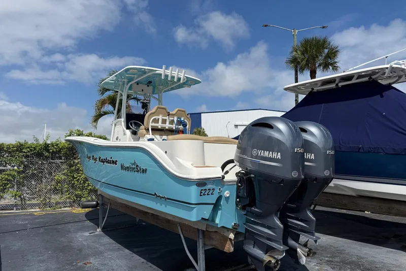 Slide: The Image of 2019 NauticStar 2602 Legacy boat with twin Yamaha engines, docked under blue sky. - 3