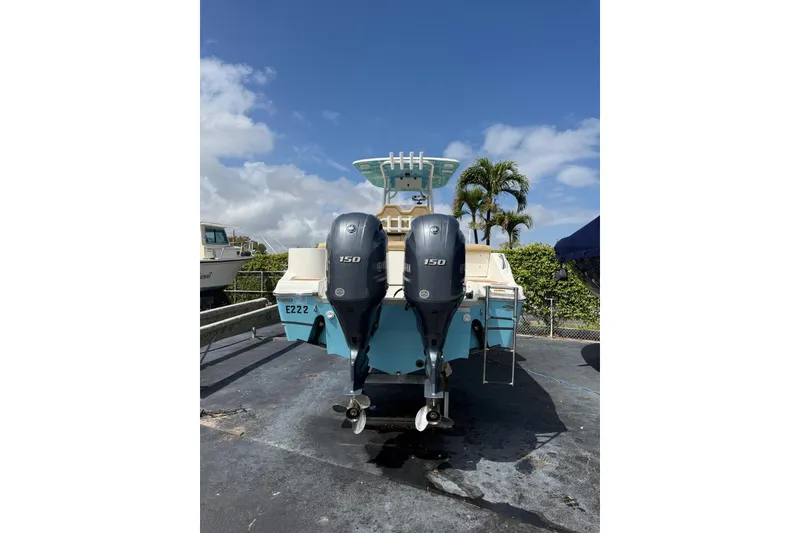 Slide: The Image of 2019 NauticStar 2602 Legacy boat with dual 150 horsepower engines, docked under a clear sky. - 6