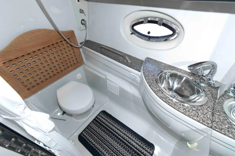 Slide: The Image of 2015 Crownline 350 SY yacht bathroom with sink, toilet, and porthole window. - 16