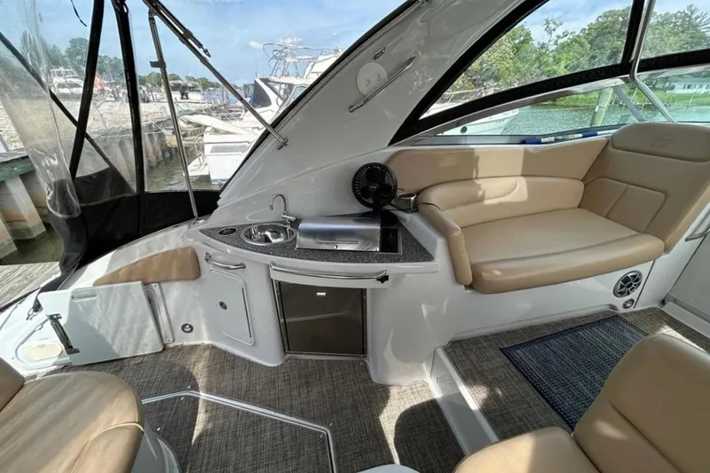Slide: The Image of 2015 Crownline 350 SY yacht interior with seating, kitchenette, and window views. - 4