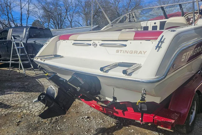 Slide: The Image of 1999 Stingray 220 CS boat on trailer, parked outdoors with a truck nearby. - 2