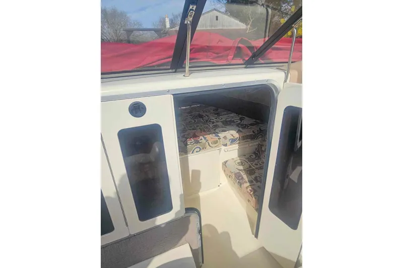 Slide: The Image of 1999 Stingray 220 CS boat cabin interior with patterned seating and open door. - 7