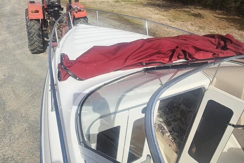 Slide: The Image of 1999 Stingray 220 CS boat with red cover, towed by a tractor on a gravel path. - 9