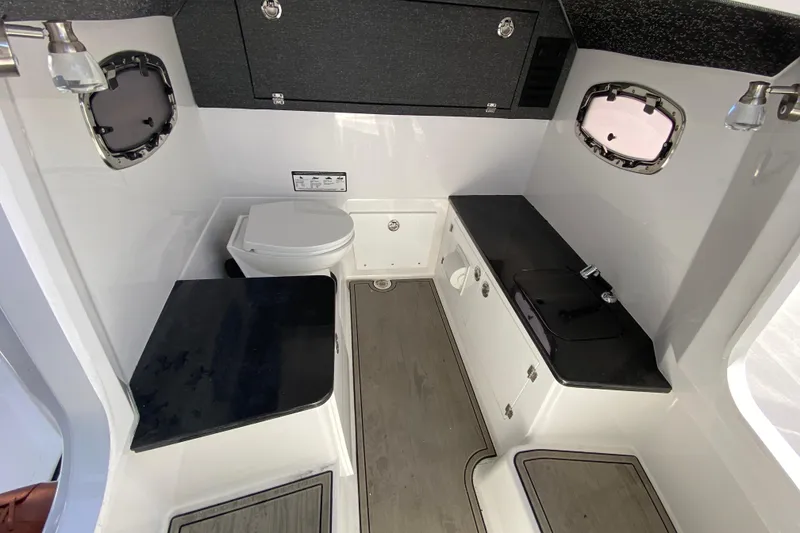 Slide: The Image of Interior of 2026 Monterey Elite 25 OB boat with compact bathroom and kitchenette. - 28