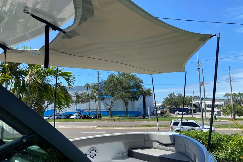 Slide: The Image of 2026 Monterey Elite 25 OB boat with sunshade canopy, parked near a road and palm trees. - 29
