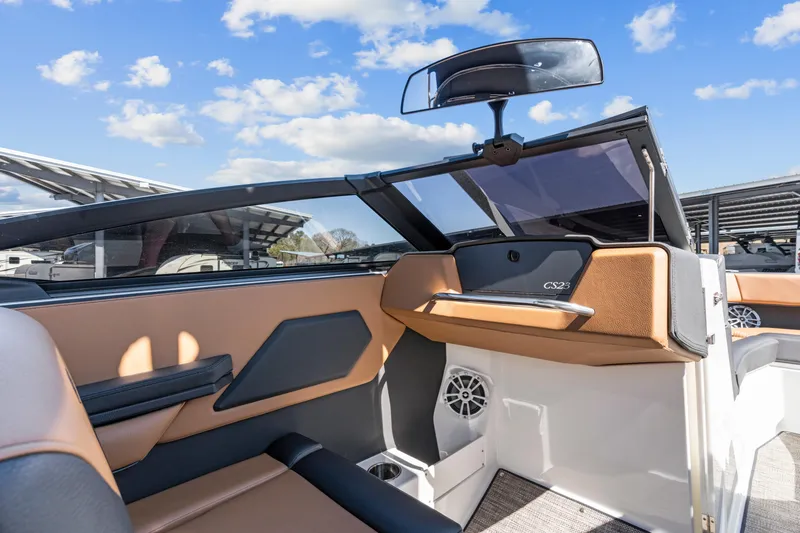 Slide: The Image of 2024 Cobalt CS23 Surf boat interior with tan and black seating under a blue sky. - 15