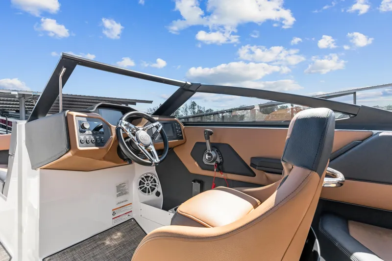 Slide: The Image of 2024 Cobalt CS23 Surf boat interior with modern dashboard and steering wheel under blue sky. - 17
